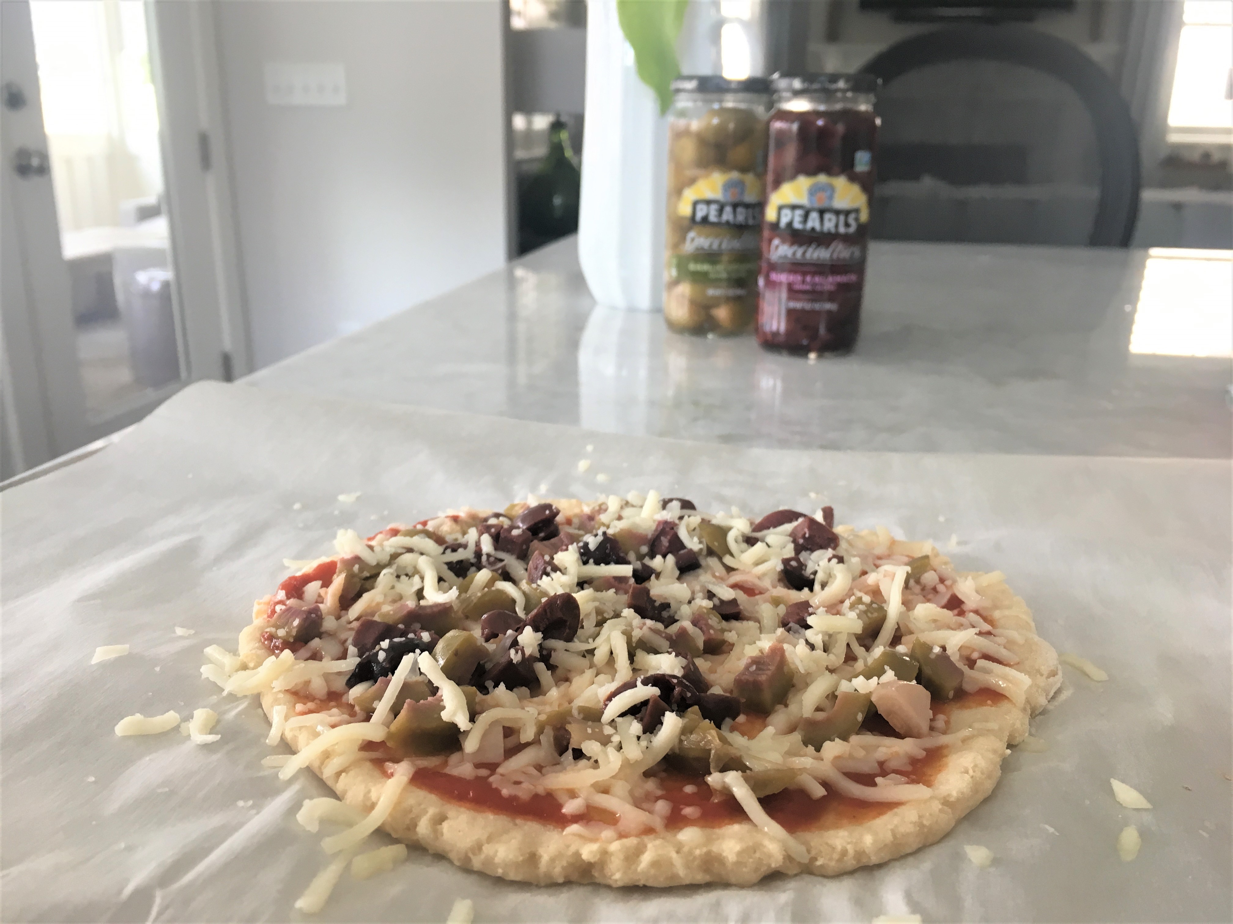 Spring time entertaining is made easy with this healthy weight watchers approved olive pizza! Check out my easy two-ingredient dough that you can make in three minutes, and tastes delicious!